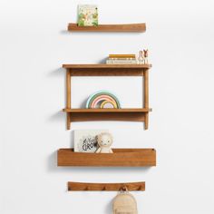 three wooden shelves on the wall with books and stuffed animals in them, one is empty