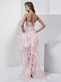 a woman in a strapless pink dress standing next to a white wall and stairs