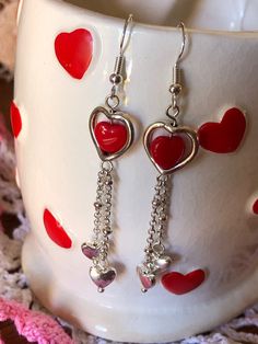 These red glass heart bead dangle earrings make a simple and delicate touch to any outfit whether you wear them for Valentine's Day or just any day. Silver-toned findings and nickel-free ear wires complete the set. Do not wear earrings when bathing or swimming. Avoid getting hairspray, perfume or lotions on them. Wipe with a soft damp cloth if required. Red Heart Charm Metal Earrings, Metal Heart Earrings With Heart Beads, Valentine's Day Dangling Charms Drop Earrings, Valentine's Day Dangling Beads Jewelry Gift, Valentine's Day Jewelry With Dangling Beads As Gift, Valentine's Day Jewelry Gift With Dangling Beads, Valentine's Day Gift Jewelry With Dangling Beads, Metal Heart Beaded Earrings For Gifts, Dangle Heart Bead Earrings Gift