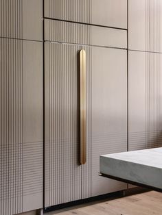 a white bed sitting next to a wall covered in metal lockers and doors with gold handles