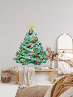 a decorated christmas tree sitting on top of a wooden table next to a white bed