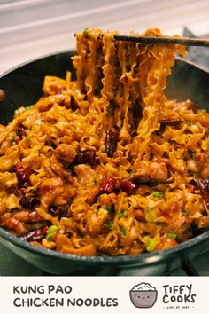 a pan filled with noodles and meat being lifted by tongs