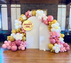 an arch made out of balloons with a sign that says groovy girl