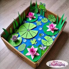 a cardboard box filled with paper cut outs and water lilies on top of it