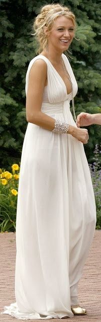 a woman in a white dress smiles as she holds the hand of another woman's hand