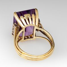 This stunning ring is centered with one (1) emerald cut natural amethyst set into a four-prong setting. The center stone is flanked to each side with a row of three (3) prong set, round brilliant cut diamonds. The ring measures 18.2mm at the top, rises 10.2mm above the finger, tapering to 4.0mm wide and 1.5mm thick at the base of the shank. It is currently a size 7.5. Cocktail Diamond Ring, Amethyst Set, Diamond Cocktail Rings, October Birth Stone, Round Brilliant Cut Diamond, High Quality Jewelry, Brilliant Cut Diamond, Emerald Cut, Estate Jewelry