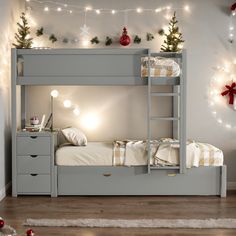 a bunk bed with christmas decorations on the wall and lights strung from the ceiling above it