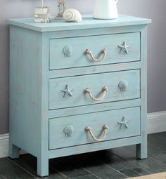 a blue chest of drawers with seashells on the top and bottom, along with a white vase