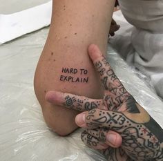 a person with tattoos on their legs holding up the word'hard to explain '