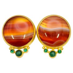 Fabulously unique statement earrings filled with exceptional color and fine details. Each singular stone has its own natural striations, varying hues and raw design, creating a truly one-of-a-kind pair. These natural beauties each feature a single round cabochon agate stone bezel set in luxurious 22 karat yellow gold. Each polished agate stone has a unique natural design, so the pair are not perfectly identical. Below the main stone is a trio of natural cabochon emeralds, beautifully complimenti Raw Design, Emerald Cabochon, Natural Design, Raw Beauty, Yellow Gold Setting, Red Agate, Pierced Earrings, Natural Emerald, Nature Design