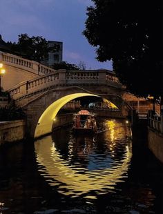 a boat traveling down a river under a bridge with lights on it's sides