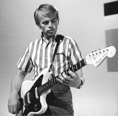 a man playing an electric guitar while wearing a striped shirt