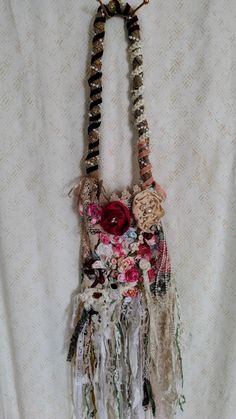 a handbag hanging on a wall with flowers and feathers attached to the back of it