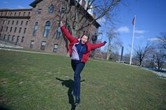 a man is jumping in the air with his arms wide open outside an old building