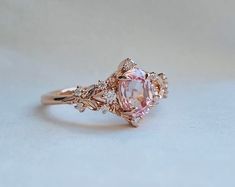 a fancy ring with an oval pink diamond surrounded by small white and rose gold diamonds