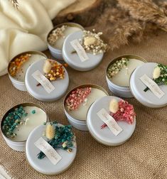 six small tins filled with different types of dried flowers and herbs on top of a table