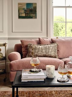 a living room with pink couches and coffee table in front of two windows on the wall