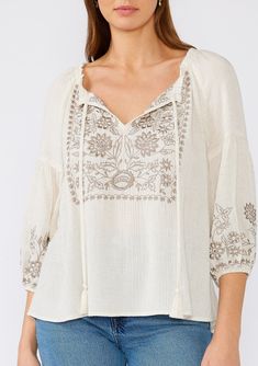 A classic bohemian peasant top is a must-have addition to your spring and summer wardrobe. Featuring an intricate embroidered detail, with a split v-neckline, tassel ties, and exaggerated voluminous 3/4 length sleeves. Try it tucked into denim, or wear it loose over shorts. Linen blend Embroidered Relaxed fit Voluminous 3/4 length long sleeve Elastic cuff Split v-neckline with tassel ties Ruffled neckline Flowy bohemian peasant top Model is 5'9, wearing a size S.Style: I-13851W-RRR Spring Vacation Peasant Top With Tassels, Spring Peasant Top With Tassels For Vacation, Spring Bohemian Embroidered Tunic Top, Vacation Peasant Top With Tassel Ties, Bohemian Spring Embroidered Tunic Top, Peasant Style Summer Blouse With Tassels, Spring Vacation Blouse With Intricate Embroidery, Cream Tops With Intricate Embroidery For Summer, Intricate Embroidery Blouse For Spring Vacation