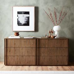 a wooden dresser with two vases on top of it next to a framed photograph