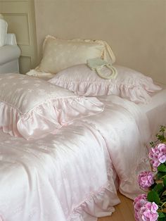 a white bed with pink flowers on the side and a pillow in the middle next to it