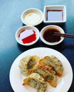 some dumplings are on a plate with dipping sauces