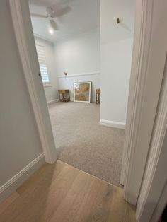 an empty living room with white walls and carpeted flooring is seen from the doorway