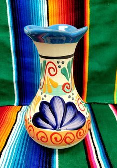 a colorful vase sitting on top of a striped cloth