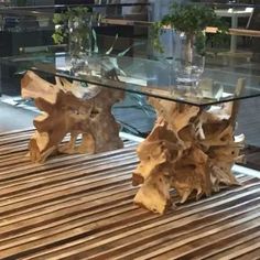 a glass table sitting on top of a wooden floor next to vases filled with flowers