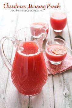 a pitcher filled with red liquid sitting on top of a table next to two glasses