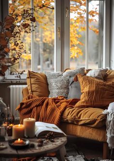 a living room filled with lots of furniture next to a window covered in fall leaves