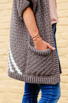 a woman is holding her hand in the pocket of a crocheted bag