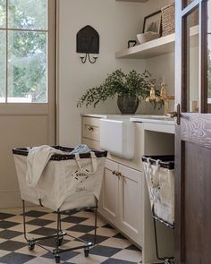 a shopping cart in the middle of a kitchen next to a sink and window with potted plants on it