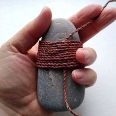 a hand holding a rope wrapped around a rock