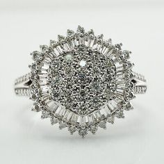 a white gold ring with diamonds on the top and side, surrounded by smaller round stones