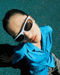 a young boy laying on the ground wearing sunglasses