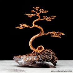 a wire tree sculpture sitting on top of a rock