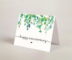 a card with the words happy anniversary written in cursive writing and green leaves