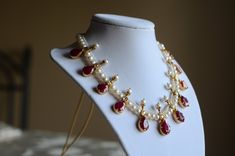 a necklace is displayed on a mannequin with pearls and garnets hanging from it