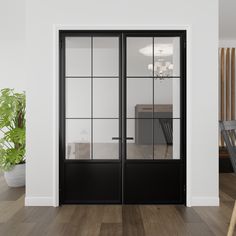 an empty room with two black doors and a wooden table in the corner, next to a potted plant