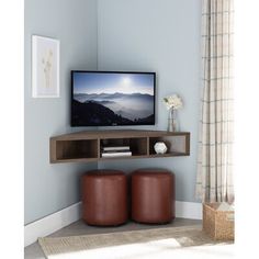 a flat screen tv sitting on top of a wooden shelf next to two stools