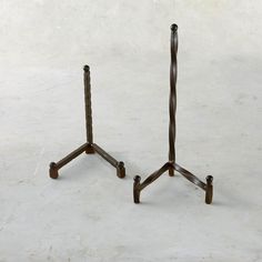 two metal stands on top of each other in front of a white wall and floor