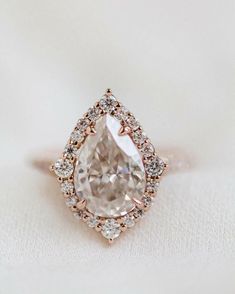 an engagement ring with a pear shaped diamond surrounded by small diamonds