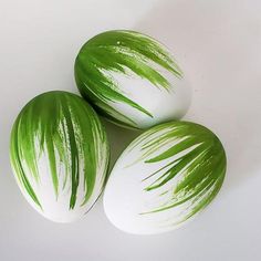 three green and white painted eggs sitting next to each other