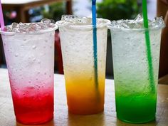 three different colored drinks sitting on top of a table