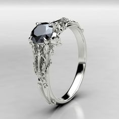 a white gold ring with two black diamonds on the front and center stone in the middle