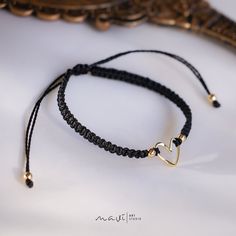 a black string bracelet with a gold heart charm