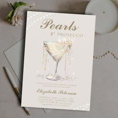 a wedding card with pearls and a champagne glass on the front, next to a candle