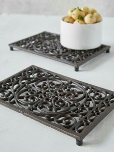 two trays with decorative designs on them and a bowl of potatoes in the background