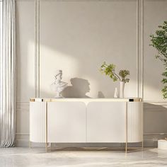 a living room with white furniture and a potted plant on the sideboard next to it