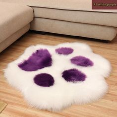 a purple and white animal print rug sitting on top of a wooden floor next to a couch